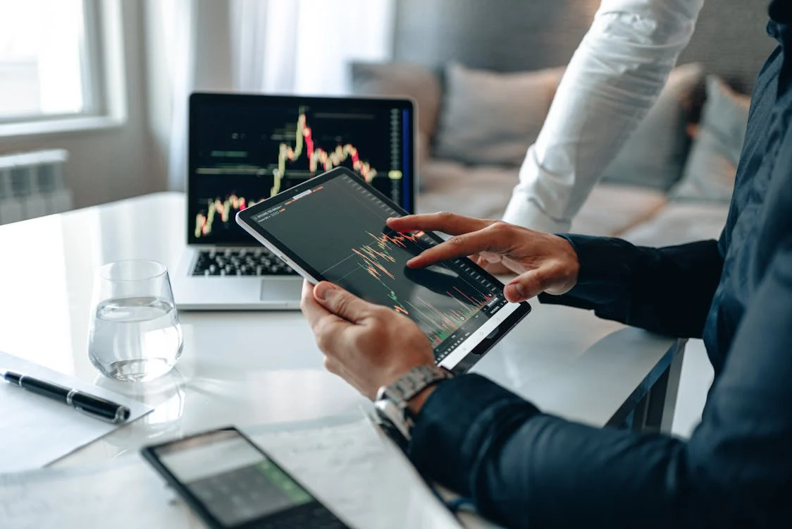person in suit discussing stock market trends on digital tablet